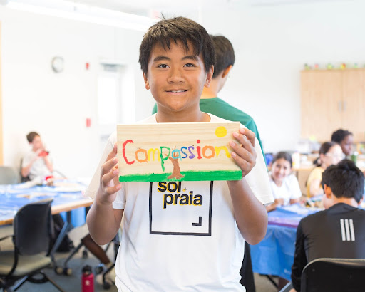 Child holding sign that says Compassion